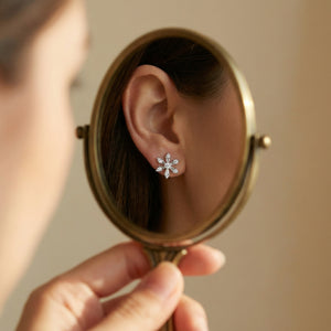 Person holding a round mirror to show a diamond earring.