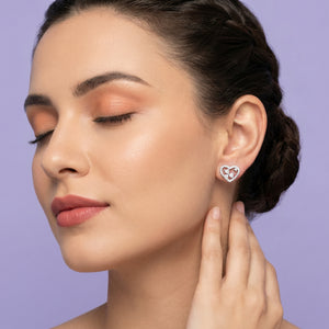 Woman wearing a heart-shaped earring against a purple background