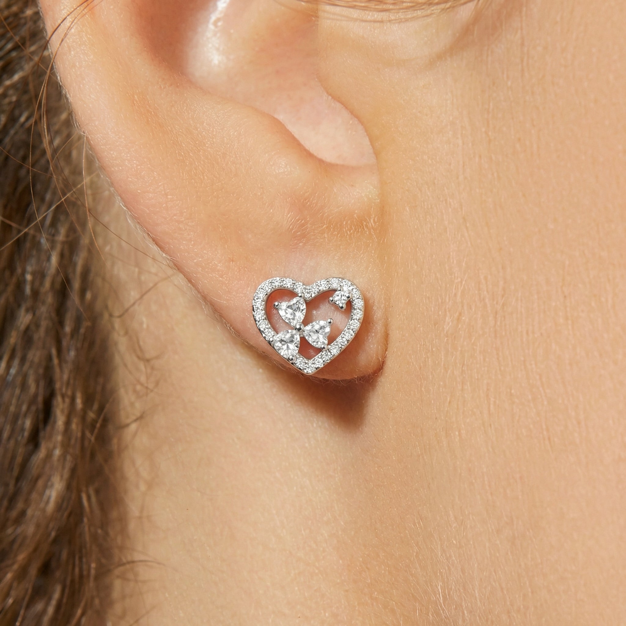 Heart-shaped earring worn on an ear with a close-up view
